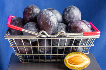 Basket of ripe plum fruits close up on a blue background