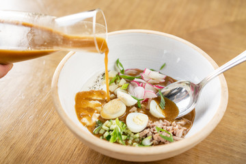 Soup okroshka. Traditional Russian summer cold dish with kvass in bowl on wooden background. Restaurant menu