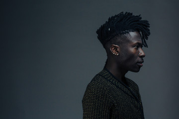 Profile portrait of a young man on dark black studio background