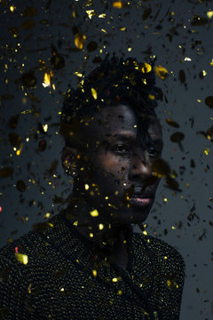 Confetti explosion, portrait of a young man with golden confetti falling