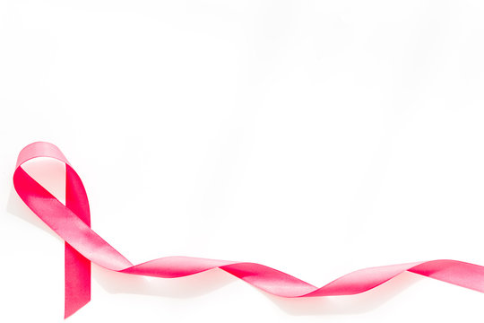Pink ribbon as symbol of breast cancer awareness on white background top view space for text