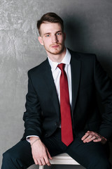 Young man in a black suit on a dark background