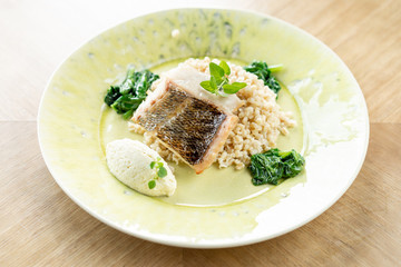 Roasted Pike perch with spelt and Polish sauce. Dish decorated with a spinach. Restaurant menu