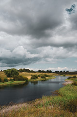 Beautiful view of river and dark stormy clouds over the land