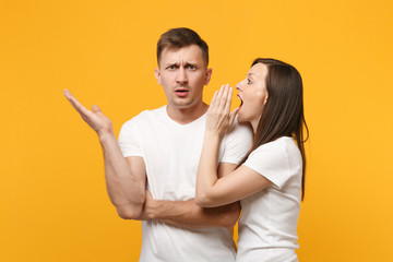 Young couple two friends guy girls in white blank empty design t-shirts posing isolated on yellow...