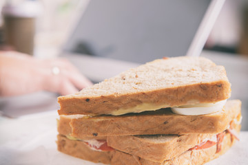 Woman eating a breakfast sandwich while working with a laptop