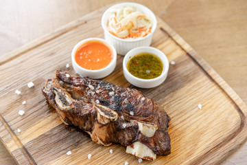 Beef meat cut according to the Argentine style, called asado. with Pickled cabbage and two sauces. Serving on a wooden Board. Barbecue restaurant menu, a series of photos of different meats.