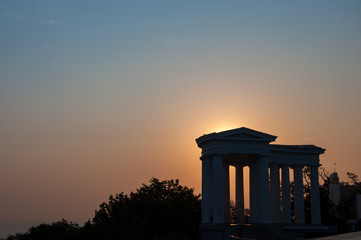 Dark silouette of the Odessa colonnade, with sun rising behind.