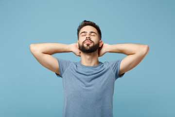 Fototapeta na wymiar Young relaxed calmed man in casual clothes posing isolated on blue wall background, studio portrait. People sincere emotions lifestyle concept. Mock up copy space. Sleeping with hands behind his head.