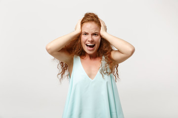 Fototapeta premium Young crazy wild redhead woman in casual light clothes posing isolated on white background in studio. People sincere emotions lifestyle concept. Mock up copy space. Screaming, putting hands on head.