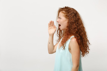 Side view of young displeased redhead woman in casual light clothes posing isolated on white background in studio. People lifestyle concept. Mock up copy space. Screaming with hand gesture near mouth.