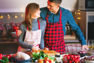 happy couple in aprons celebrating Christmas in the kitchen cooking christmas duck or Goose