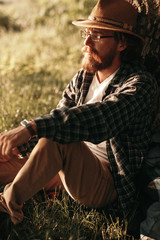 Bearded hiker sitting under tree in nature