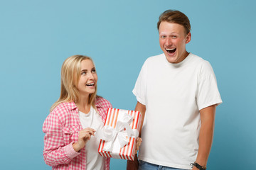Young laughing couple two friends guy girl in white pink t-shirts posing isolated on blue...