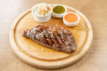 Grilled striploin steak with Pickled cabbage and two sauces. The strip steak, also called a New York strip. Serving on a wooden Board. Barbecue restaurant menu, a series of photos of different meats.