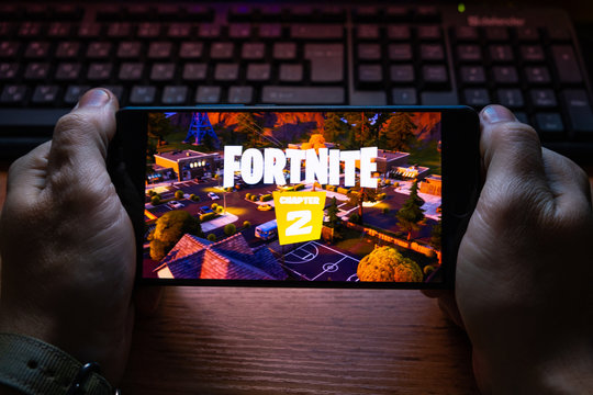 Kostanay, Kazakhstan, October 15, 2019.A man holds a mobile phone with a screensaver of the popular game Fortnite 2, from Epic Games.