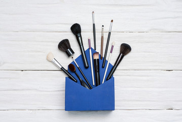 Make up background. Brushes for makeup on the white wooden table.