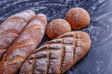 Bakery - gold rustic crusty loaves of bread and buns on black chalkboard background.