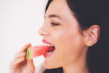 happy young woman is eating slice of watermelon over white background