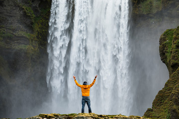 Man admirnig the beauty of iconic Skogafoss waterfall in Iceland, Europe. - Powered by Adobe