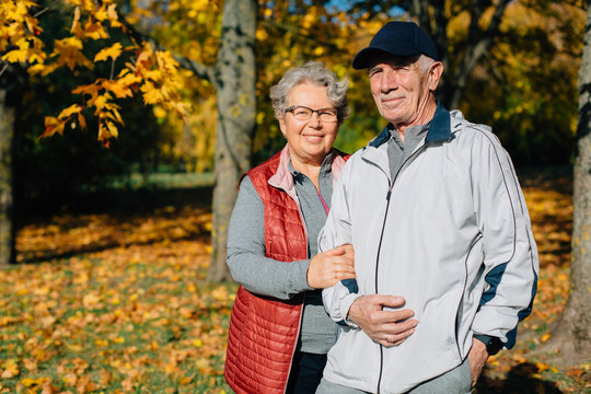 Pretty senior couple having fun in autumn park. Mature woman and old man resting outdoors.