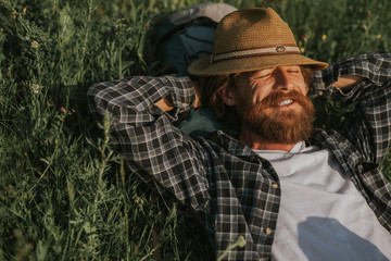 Bearded traveler relaxing on grass in nature