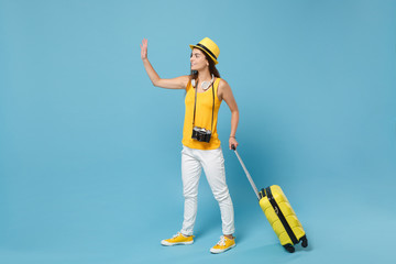 Traveler tourist woman in yellow casual clothes, hat with suitcase photo camera isolated on blue background. Female passenger traveling abroad to travel on weekends getaway. Air flight journey concept