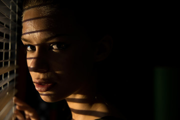 poster style Portrait of young woman looking through  sun blinds window shutter artistic version 