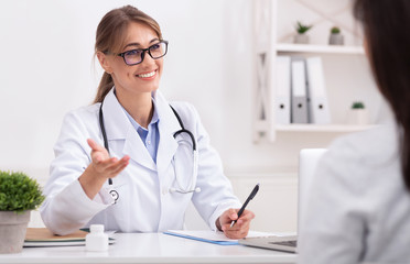 Cheerful Doctor Lady Talking With Patient Suggesting Treatment In Office