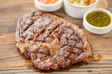 Sliced medium rare grilled Steak Ribeye with Pickled cabbage and two sauces. Serving on a wooden Board. Barbecue restaurant menu, a series of photos of different meats.
