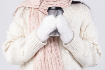 Closeup studio photoyoung caucasian woman holding coffee trying to get warm. Holding cup with hands...