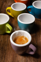 Various colored coffee cups and a cup with steaming espresso coffee