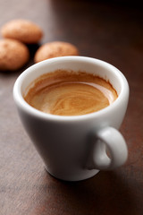 Cup of coffee with amaretti (Italian biscuits) on rustic wooden background. Close up.