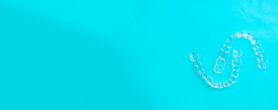 Invisible dental teeth brackets tooth aligners on blue background, plastic braces dentistry retainers to straighten teeth. Orthodontic temporary removable straighteners in dentist office dental