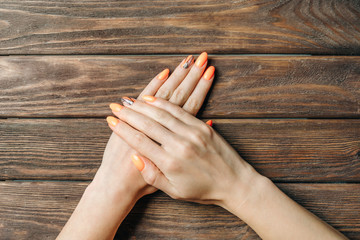 Female hands with professional beautiful manicure of orange color.