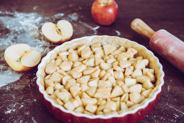 Traditional homemade apple pie and ingredients on wooden background for autumn holiday