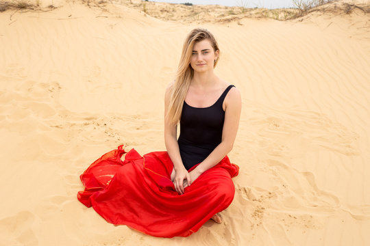 a young girl in the desert is wrapped in beautiful red developing silk - Powered by Adobe