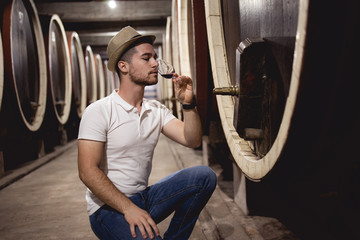 Obraz na płótnie Canvas Winemaker working in oak barrels at cellar stock photo