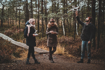 Bearded student is making photo using his drone, while his friends are watching something on the tablet.