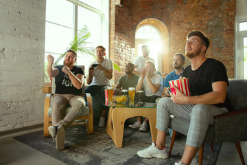 Obraz premium Grupa podekscytowanych przyjaciół grających w gry wideo w domu. Kaukascy gracze lub fani spędzający czas i dobrze się bawiąc w domu. Emocjonalna rozgrywka podczas oglądania. Nowoczesne technologie, przyjaźń, weekend
