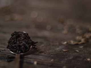 teaspoon full of tea leaf on a wooden table. black tea in a spoon. Dry black tea leaves on metal...