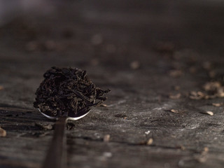 teaspoon full of tea leaf on a wooden table. black tea in a spoon. Dry black tea leaves on metal...