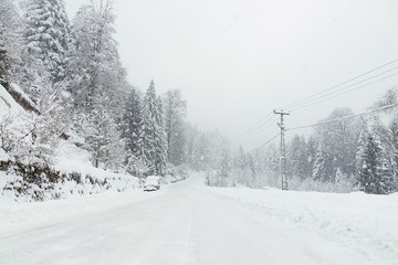 Fototapeta premium Snowy road in winter with an SUV parked.