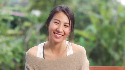Asian woman feeling happy smiling and looking to camera while relax on table in garden at home in...