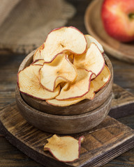 Apple chips in a wooden bowl on a wooden table. Rustic style
