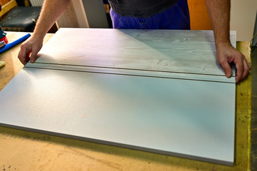 The worker makes, assembles a furniture cabinet from parts. Showing tools for work. The photo was taken in a really working manufactory.