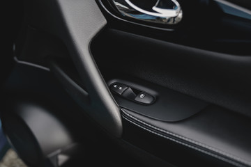 Fototapeta na wymiar Control panel in the car door. Car door handle with adjustment knobs.