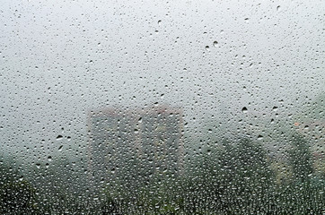 Raindrops on a window pane overlooking the city and trees