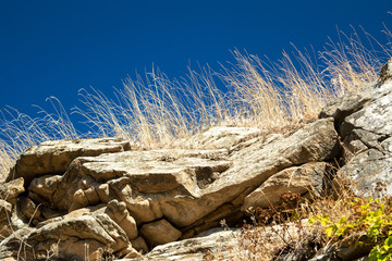 Cliff edge with dry grass on blue sky