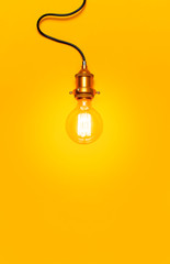 Vintage fashionable edison lamp on bright yellow background. Top view flat lay copy space. Creative idea concept, designer lamp, modern interior item. Lighting, electricity, background with lamp
